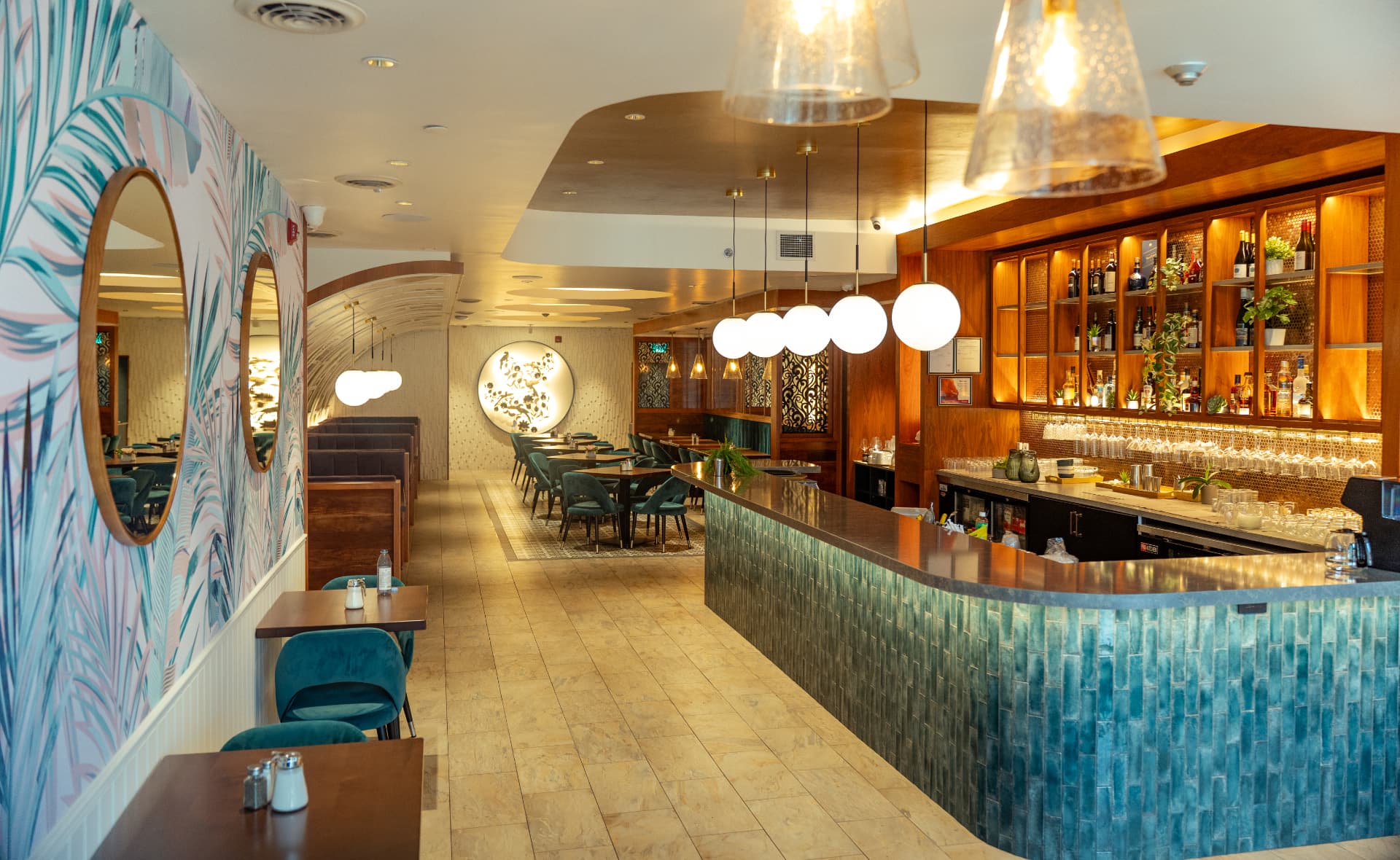 SOLENA's teal-tiled bar with backlit bottle shelving, globe pendants and palm-print mural