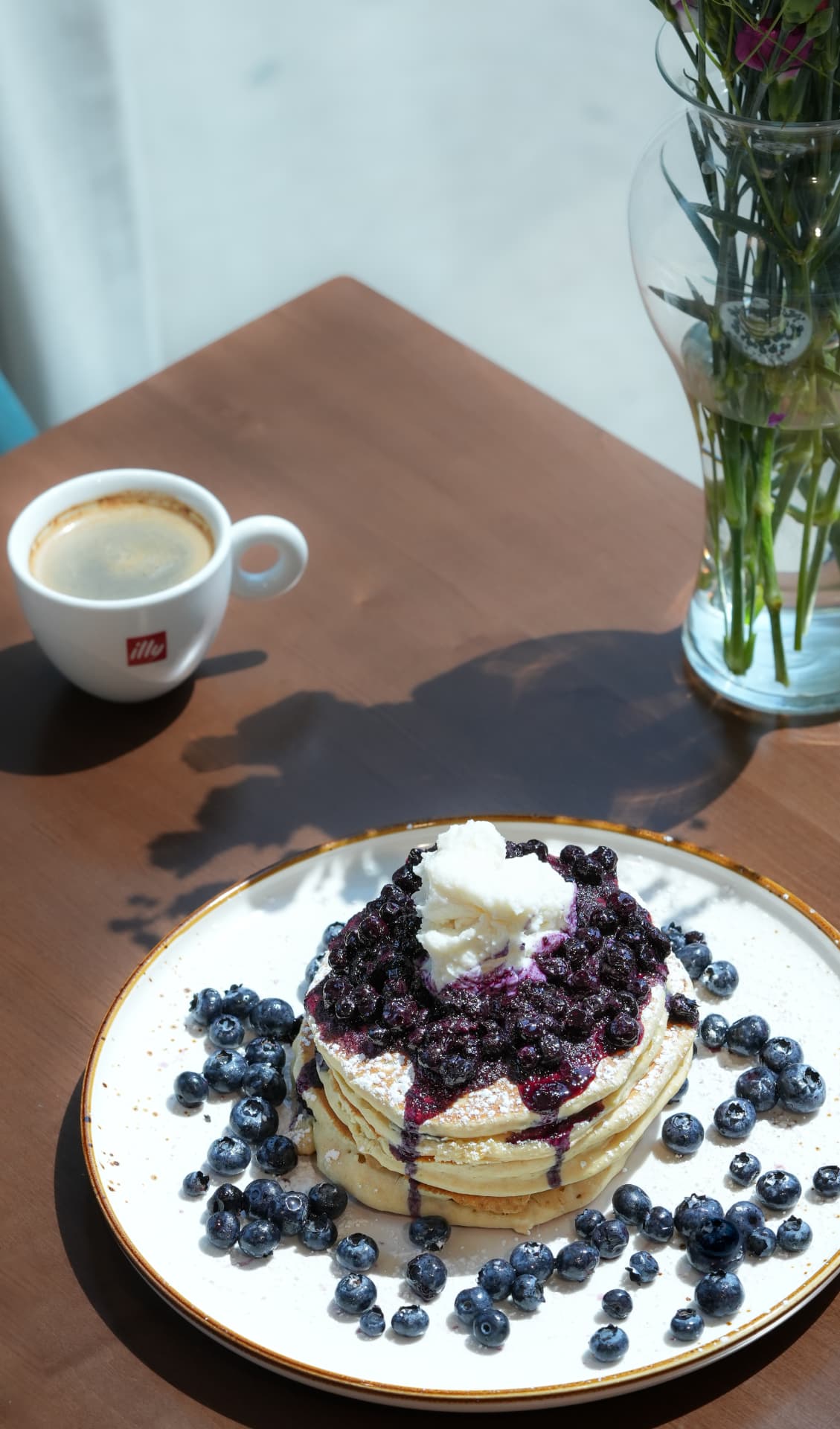 Blueberry pancake stack with whipped ricotta beside an espresso in morning light at SOLENA