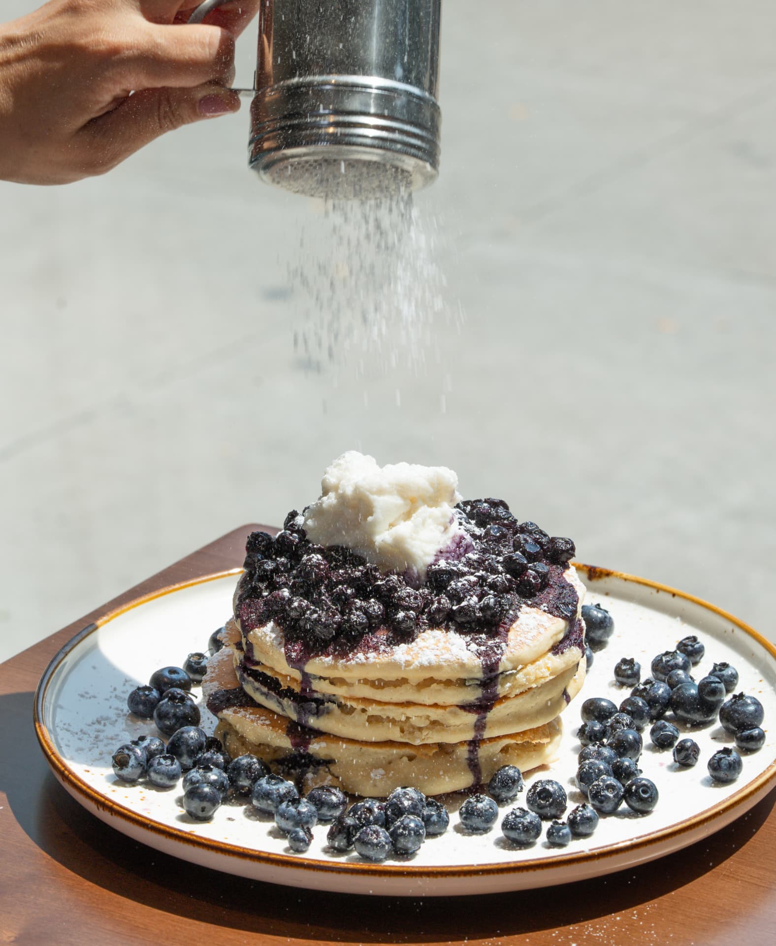Icing sugar dusted over a blueberry pancake stack ringed with fresh blueberries at SOLENA Brunch & Bar