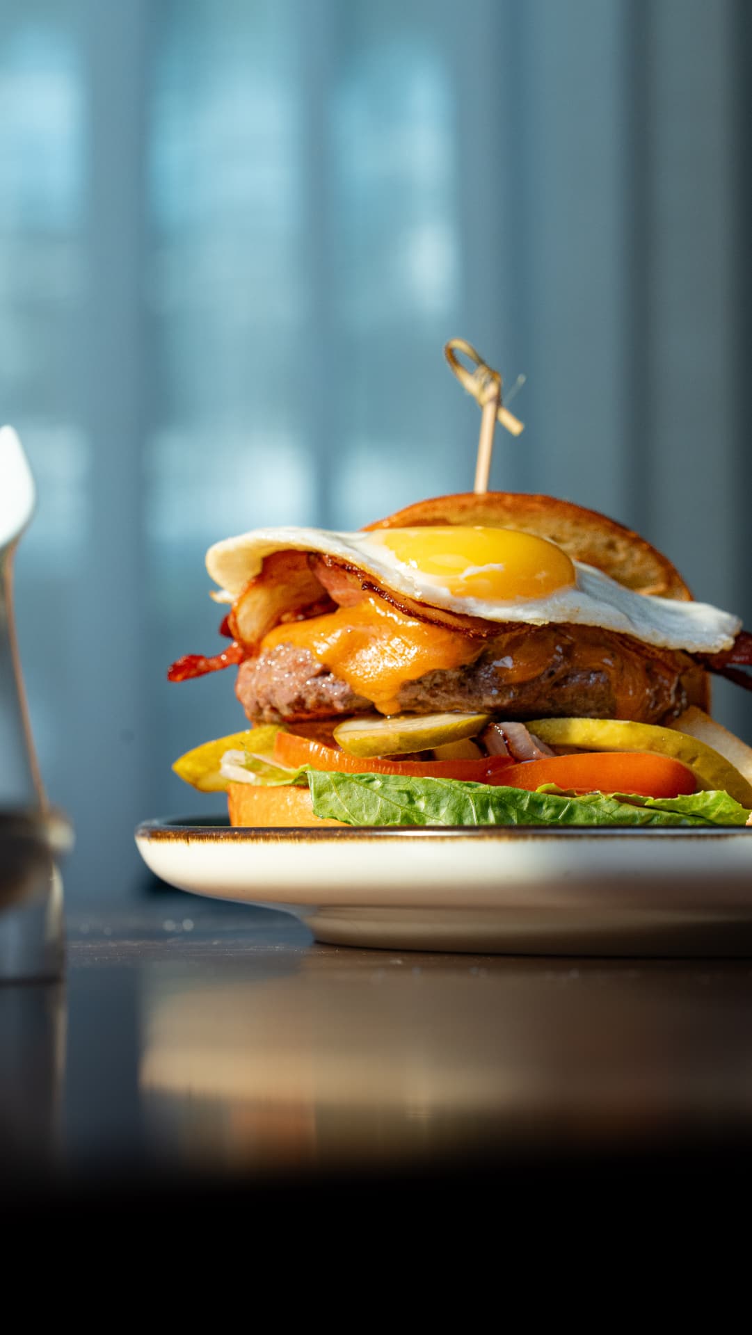 SOLENA brunch burger with bacon, melted cheddar and a fried egg on a toasted brioche bun