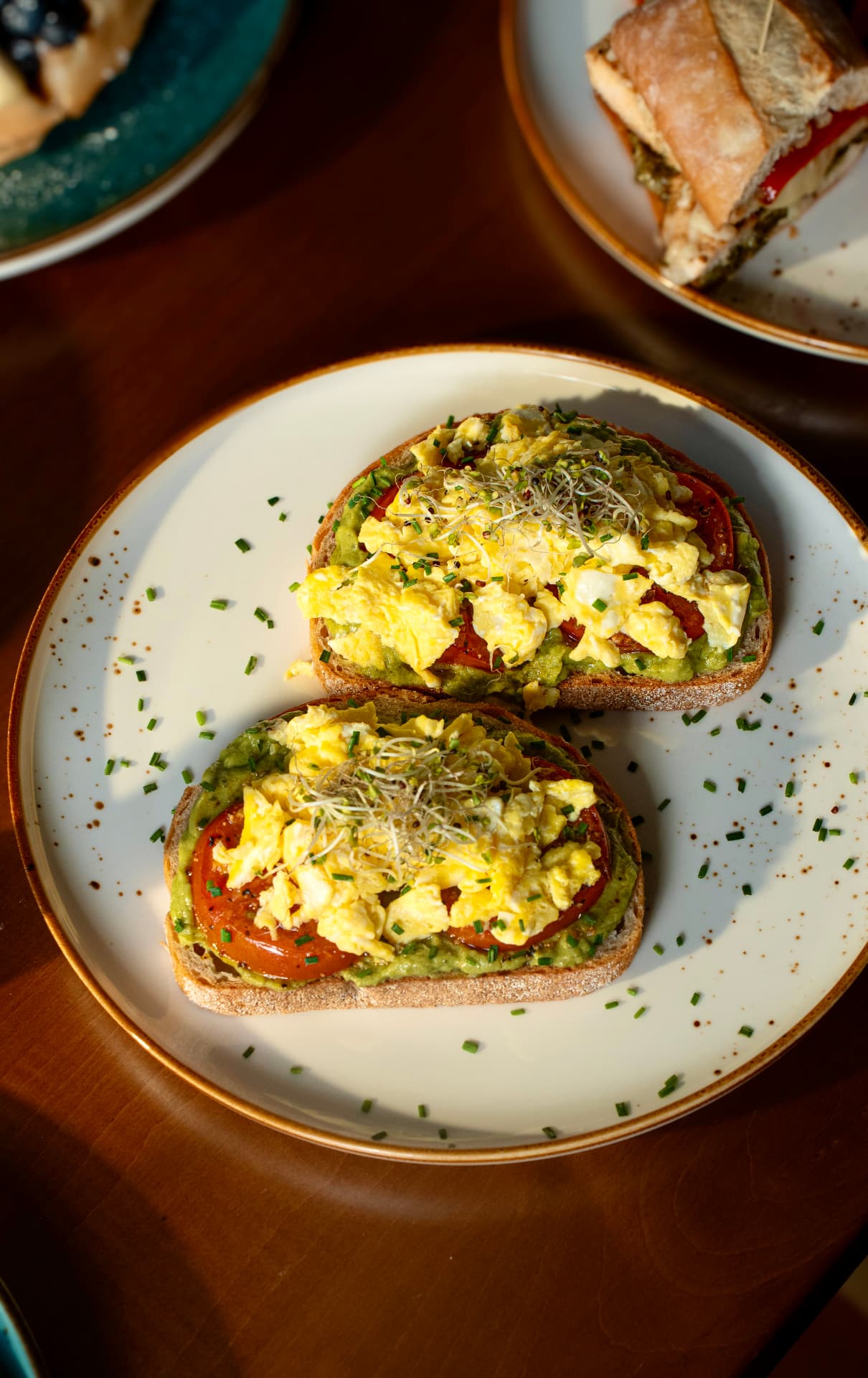 Avocado toast topped with soft scrambled eggs, roasted tomato, chives and sprouts at SOLENA